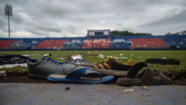 Discarded shoes sit by the pitch at Kanjuruhan stadium days after a deadly stampede following a football match in Malang, East Java on October 3, 2022. Anger against police mounted in Indonesia on October 3 after at least 125 people were killed in one of the deadliest disasters in the history of football, when officers fired tear gas in a packed stadium, triggering a stampede. (Photo by Juni Kriswanto / AFP)