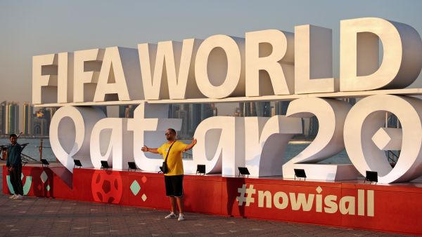 A man (C) has his photos taken with a FIFA World Cup sign in Doha on November 16, 2022, ahead of the Qatar 2022 World Cup football tournament. (Photo by Adrian DENNIS / AFP)