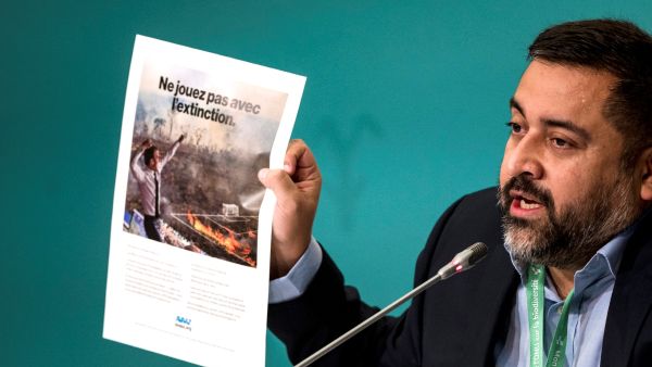 Campaign Director for the international activist group Avaaz, Oscar Soria, shows a advertisement calling out President Emanuel Macron for not being at COP15 during a press conference at the United Nations Biodiversity Conference (COP15) in Montreal, Quebec, Canada on December 14, 2022. (Photo by ANDREJ IVANOV / AFP) French president