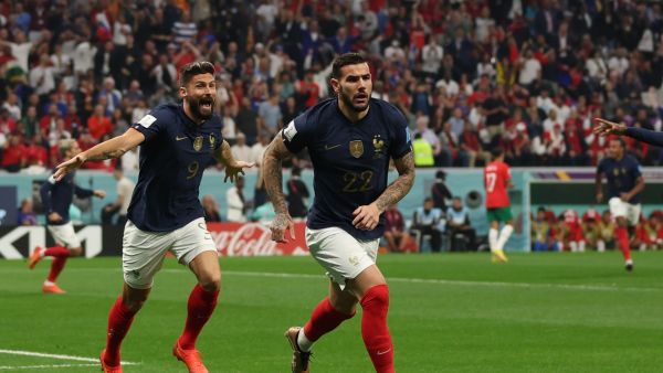 France's defender #22 Theo Hernandez celebrates, with France's forward #09 Olivier Giroud running behind, after scoring his team's first goal during the Qatar 2022 World Cup semi-final football match between France and Morocco at the Al-Bayt Stadium in Al Khor, north of Doha on December 14, 2022. (Photo by Adrian DENNIS / AFP)
