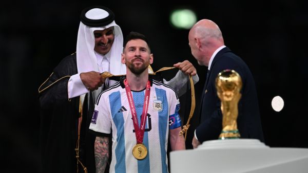 Qatar's Emir Sheikh Tamim bin Hamad al-Thani (L) wraps an abaya around Argentina's forward #10 Lionel Messi on stage next to the FIFA World Cup Trophy after Argentina won the Qatar 2022 World Cup final football match between Argentina and France at Lusail Stadium in Lusail, north of Doha on December 18, 2022. (Photo by Paul ELLIS / AFP)