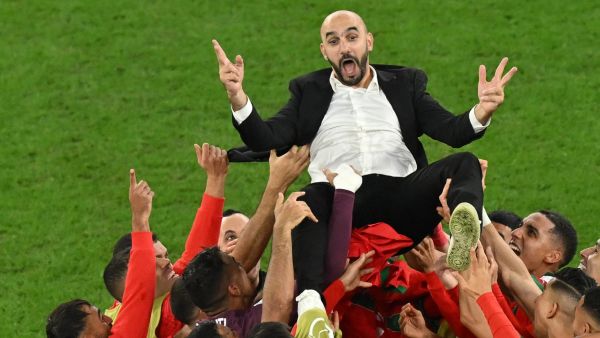 Morocco's players throw Morocco's coach Walid Regragui in the air as they celebrate at the end of the Qatar 2022 World Cup round of 16 football match between Morocco and Spain at the Education City Stadium in Al-Rayyan, west of Doha on December 6, 2022. (Photo by Glyn KIRK / AFP)
