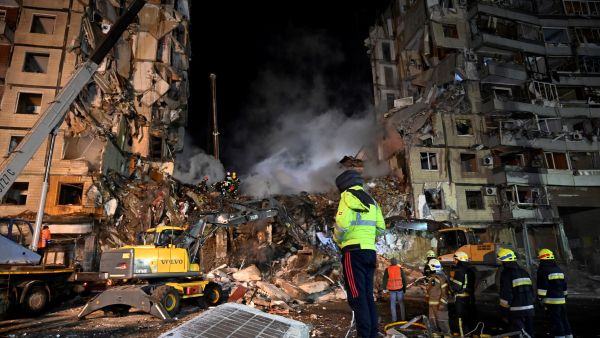 Rescuers work on a residential building destroyed after a missile strike, in Dnipro on January 15, 2023. (Photo by SERGEI CHUZAVKOV / AFP) residential building