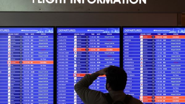 A traveler looks at a flight information board at Ronald Reagan Washington National Airport on January 11, 2023 in Arlington, Virginia. Alex Wong/Getty Images/AFP Conspiracy theories