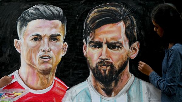 An art school student gives final touches to painting of football players Portugal's Christiano Ronaldo (L) and Argentina's Lionel Messi ahead of the Qatar 2022 World Cup football tournament in Mumbai on November 18, 2022. (Photo by INDRANIL MUKHERJEE / AFP)