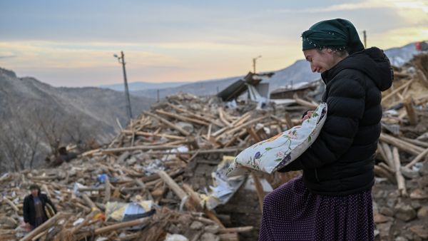 امرأة تبكي وهي تجمع متعلقاتها الشخصية فوق أنقاض منزلها المنهار عقب زلزال تركيا