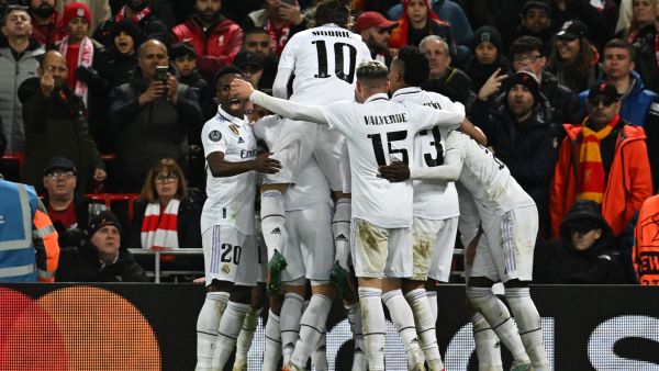 Real Madrid's French forward Karim Benzema is mobbed by teammates after scoring the team's third goal during the UEFA Champions League last 16 first leg football match between Liverpool and Real Madrid at Anfield in Liverpool, north west England on February 21, 2023. (Photo by Paul ELLIS / AFP)