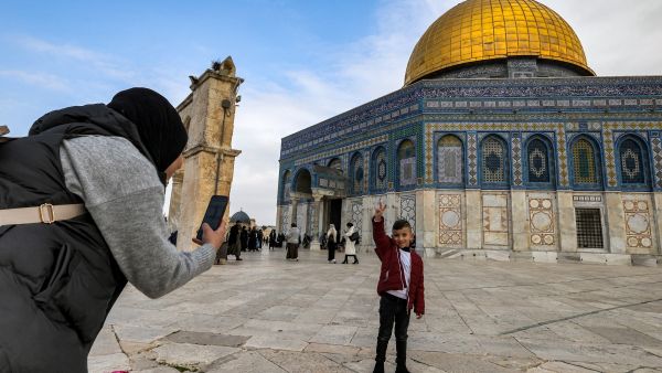 امرأة تلتقط صورة لطفل يقف أمام قبة الصخرة المشرفة