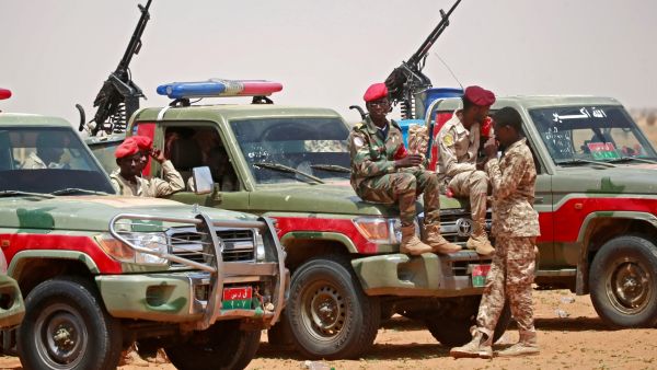 Members of Sudanese paramilitary Rapid Support Forces (RSF) celebrate as they lead dozens of African nationals, caught as they tried to cross into Libya illegally, in front of the media a desert area called Gouz Abudloaa. AFP / ASHRAF SHAZLY sudan army