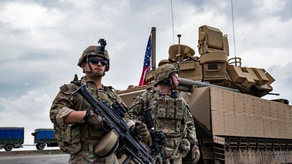 U.S. army soldiers stand near an armoured military vehicle on the outskirts of Rumaylan in Syria's northeastern Hasakeh province, bordering Turkey, on March 27, 2023. (Photo by Delil souleiman / AFP) ISIS leader
