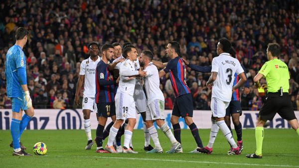 Spanish referee Ricardo De Burgos Bengoetxea shows a yellow card as players argue during the Spanish league football match between FC Barcelona and Real Madrid CF at the Camp Nou stadium in Barcelona on March 19, 2023. (Photo by LLUIS GENE / AFP)
