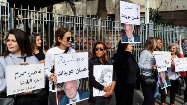 Lebanese demonstrators lift placards demanding top prosecutor Ghassan Oueidat be discharged and held accountable for the 20202 port blast.  (Photo by ANWAR AMRO / AFP) Beirut Blast