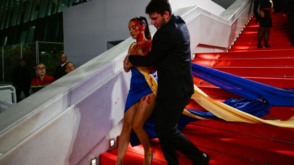 A woman dressed in Ukrainian colours pours fake blood on herself