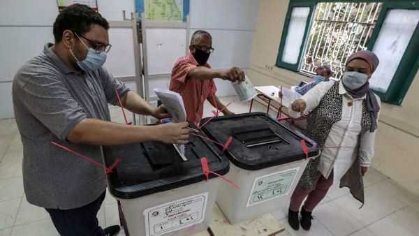 Voters, mask-clad due to the COVID-19 coronavirus pandemic, cast their ballots at a polling station in the Egyptian capital's twin city of Giza. (AFP / Mohamed el-Shahed) Ballots