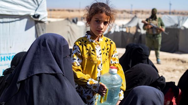 A girl looks on while holding a water container as members of the Syrian Kurdish Asayish security forces inspect tents at the Kurdish-run al-Hol camp. (Photo by Delil SOULEIMAN / AFP) ISIS members