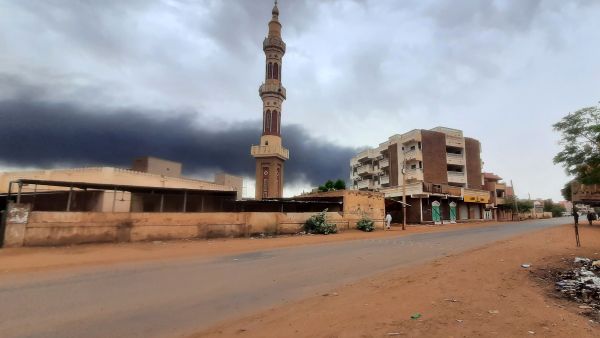 Smoke rises above buildings behind a nearly deserted street in Khartoum. (Photo by AFP) Khartoum