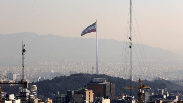 A general view shows the Iranian capital Tehran on January 7, 2023, with the Iranian flag fluttering in the wind. (Photo by ATTA KENARE / AFP) tehran