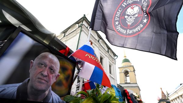 Flag bearing the logo of private mercenary group Wagner flutters above a portrait of late head of Wagner paramilitary group, Yevgeny Prigozhin at a makeshist memorial in Moscow, on August 27, 2023. (Photo by NATALIA KOLESNIKOVA / AFP) Wagner group leader Yevgeny Prigozhin