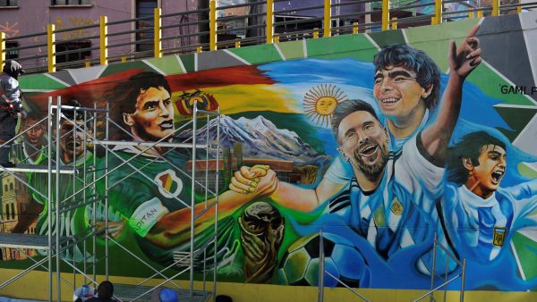 Local artists paint a mural depicting Argentine players Lionel Messi (3-R), Mario Kempes (R) and late Diego Maradona and Bolivia's Marco Antonio Etcheverry, Carlos Borja and Ramiro Castillo, in La Paz on September 10, 2023, ahead of the 2026 FIFA World Cup South American qualifier football match between Bolivia and Argentina on September 12. (Photo by JORGE BERNAL / AFP)