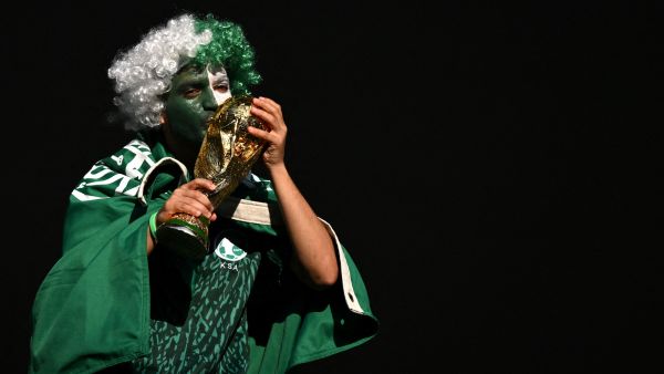 A Saudi Arabia fan kisses a replica of the FIFA World Cup trophy ahead of the Qatar 2022 World Cup Group C football match between Poland and Saudi Arabia at the Education City Stadium in Al-Rayyan, west of Doha on November 26, 2022. (Photo by Glyn KIRK / AFP)