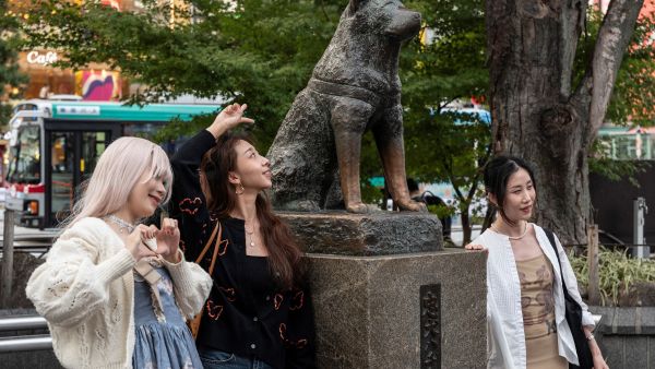 People posing for photos next to the statue of "Hachiko" in front of Shibuya station in central Tokyo