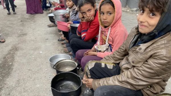 أطفال ينتظرون دورهم للحصول على بعض الطعام في غزة (الجزيرة)