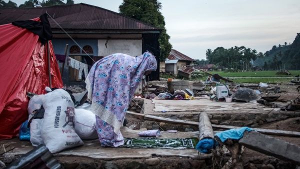 A Muslim woman offers prayers during the Islamic holy month of Ramadan as she and her family members live in the temporary shelters after a flash flood destroyed their home in Ganting, West Sumatra on March 14, 2024. (Photo by REZAN SOLEH / AFP) Indonesia landslide leaves dozens killed