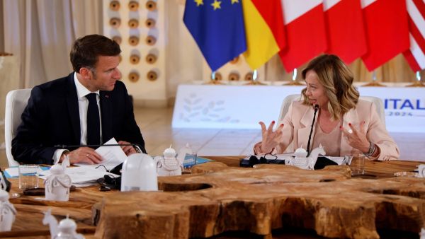 French President Emmanuel Macron (L) speaks with Italy's Prime Minister Giorgia Meloni 