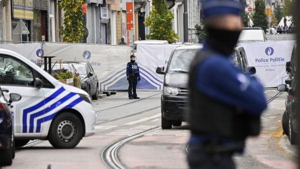 Police officers stand guard in front of the house in the Schaerbeek area of Brussels on October 17, 2023, where the suspected perpetrator of the attack in Brussels was shot dead during a police intervention. (Photo by JOHN THYS / AFP) Belgium