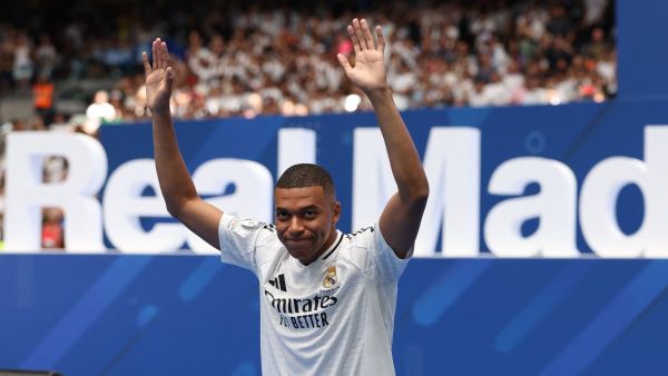 French forward Kylian Mbappe waves to the fans during a first appearance as a Real Madrid player at the Santiago Bernabeu Stadium in Madrid on July 16, 2024, after signing his new five-season contract. Still celebrating Spain's Euro 2024 triumph, Real Madrid fans have even more to cheer this July 16, 2024, as French superstar Kylian Mbappe is officially presented to a packed-out Santiago Bernabeu stadium. (Photo by Pierre-Philippe MARCOU / AFP
