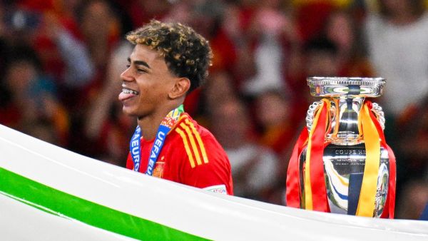 Spain's forward #19 Lamine Yamal reacts next to the trophy after winning the UEFA Euro 2024 final football match between Spain and England at the Olympiastadion in Berlin on July 14, 2024. (Photo by Jewel SAMAD / AFP)