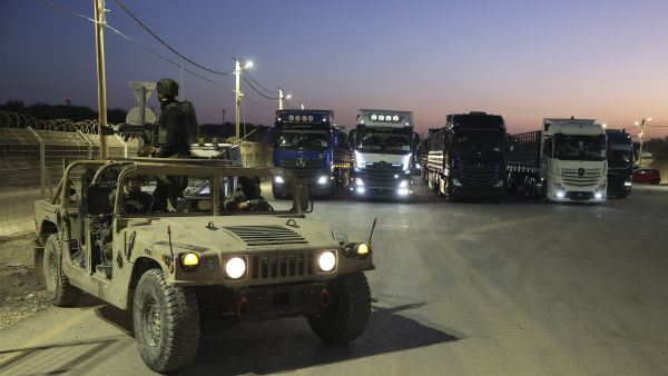 Israeli soldiers sit in an army vehicle near trucks loaded with humanitarian aid delivered from Jordan waiting to cross into Gaza on the border between Israel and the northern Gaza Strip, through the Israeli-controlled Erez crossing on October 21, 2024, amid the ongoing war between Israel and the militant group Hamas. (Photo by Jack GUEZ / AFP)