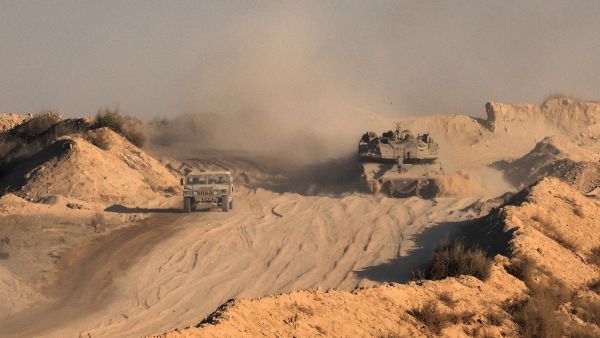 An Israeli army tank rolls near a jeep at the border with the Gaza Strip in southern Israel, on August 29, 2025, amid the ongoing war between Israel and the Palestinian militant group Hamas. The Israeli military declared Gaza City "a dangerous combat zone" on August 29, as it prepared to conquer the Palestinian territory's largest city after almost two years of war. (Photo by Jack GUEZ / AFP) Gaza city faces massive destruction as Israel uses remote-controlled robots