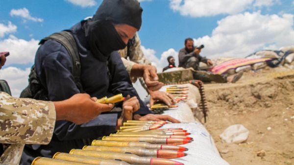 A soldier in an ISIS uniform prepares ammunition