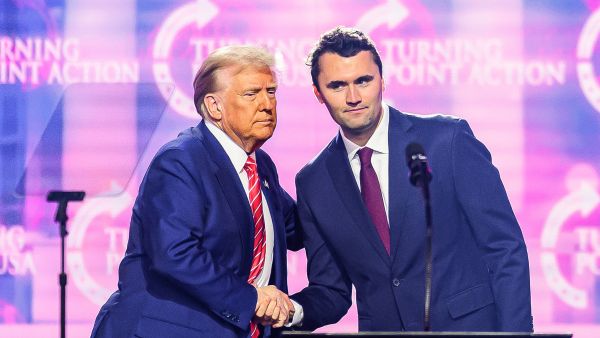 US right-wing activist Charlie Kirk (R) speaks on stage with President Donald Trump