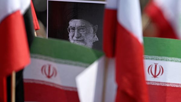 A protestor holds a placard with an image of the late Iranian Supreme Leader Ayatollah Ali Khamenei surrounded by Iranian flags outside the US consulate during a protest against the conflict in the Middle East in Mexico City on March 7, 2026. (Photo by Carl de Souza / AFP)