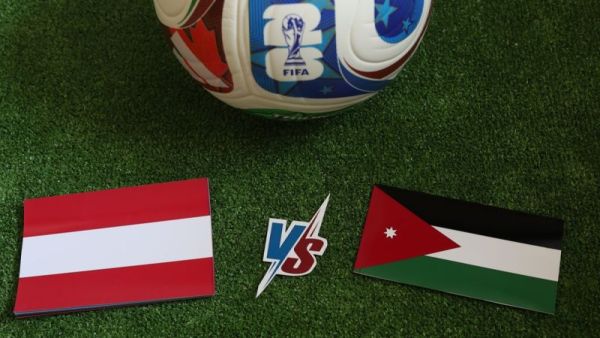 علم الأردن وعلم النمسا على أرضية ملعب كرة قدم مع كرة تحمل شعار كأس العالم قبل المباراة بين المنتخبين.