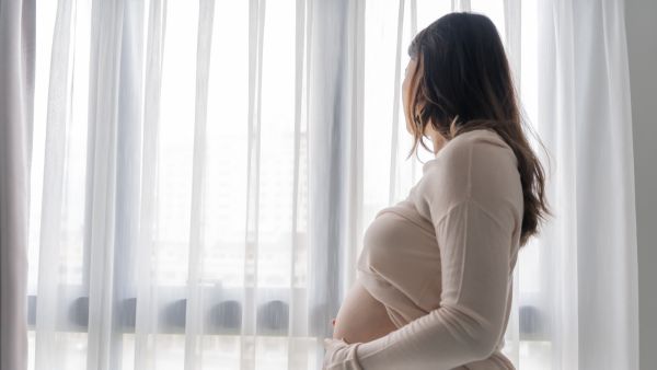 امرأة حامل بعد سن الأربعين تبتسم وتمسك بطنها 