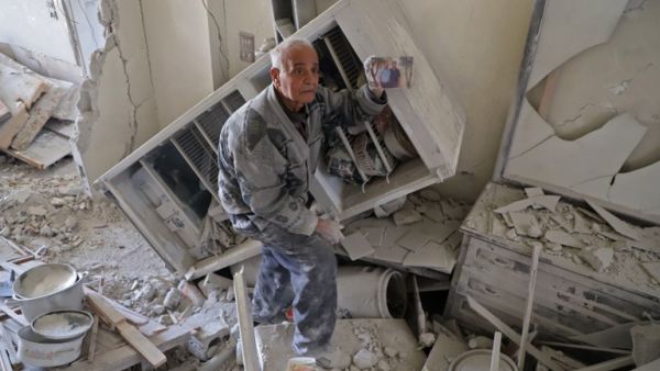 An elderly Syrian man shows a family picture after he recovered it from the rubble of his house in Kafar Batna in the Syrian rebel enclave of Eastern Ghouta on Mar. 1, 2018 following reported air strikes by Syrian government forces. 
Syrian and Russian forces kept up military pressure on rebel-held Eastern Ghouta today as their controversial unilateral truce failed to yield a humanitarian breakthrough.
(AMER ALMOHIBANY / AFP)