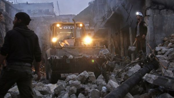 Members of the Syrian civil defence use a bulldozer to clear rubble as they search for survivors in the aftermath of an air strike in the rebel-held town of Harem in the northwestern Idlib province on Mar. 22, 2018. 
(Aaref WATAD / AFP)