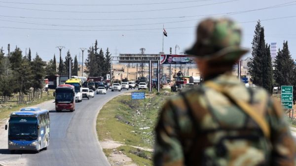 A convoy transporting Jaish al-Islam fighters and their families from the former bastion's main town of Douma arrives at the entrance to the northern Syrian city of Aleppo after being evacuated from the last rebel-held pocket in Eastern Ghouta on Apr. 3, 2018. 
(George OURFALIAN / AFP)