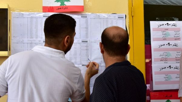 Voters check their names in the voters list at a polling station set up at the Lebanese School (AFP/File Photo)	