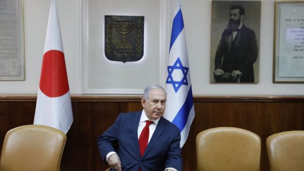 Israeli Prime Minister Benjamin Netanyahu sits in conference room before flags of Japan (L), Israel (C), and a portrait of Theodor Herzl (seen as "Visionary of the Jewish State" and founder of modern Zionism) at the PM office ahead of his meeting with his Japanese counterpart in Jerusalem on May 2, 2018. 
(Abir SULTAN / POOL / AFP)