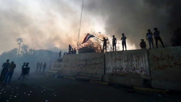 Iraqi protesters wave a national flag while demonstrating outside the burnt-down local government headquarters in the southern city of Basra on September 7, 2018. (Haidar MOHAMMED ALI / AFP)