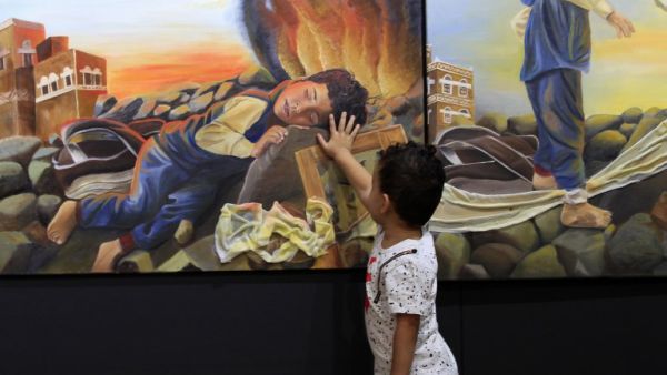 A Yemeni child touches an art work at an art exhibition against war by Yemeni painters at the People's Development Foundation in the Yemeni capital of Sanaa on October 1, 2018 (AFP)