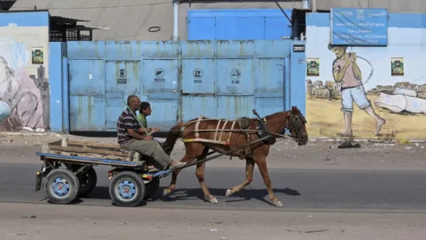 Men on a horse-drawn cart pass in front of an aid distribution center run by the United Nations Relief and Works Agency (UNRWA) in Gaza City (AFP)