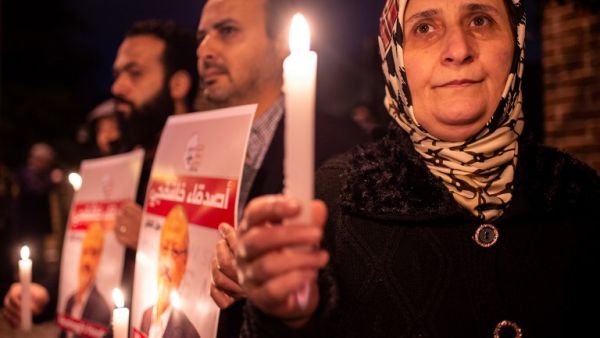 People hold posters picturing Saudi journalist Jamal Khashoggi and lightened candles during a gathering outside the Saudi Arabia consulate in Istanbul, on October 25, 2018. (asin AKGUL / AFP)