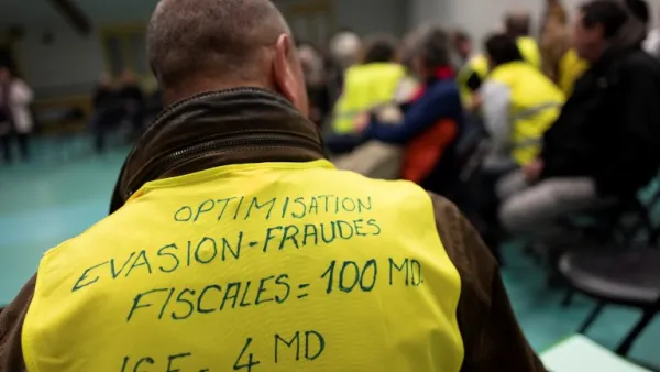A man wearing a yellow vest with a slogan reading in French "Optimisation, tax avoidance = 100 billions, ISF = 4 billions) attends a meeting called by local members of the "yellow vest" (Gilets Jaunes) movement. (AFP)