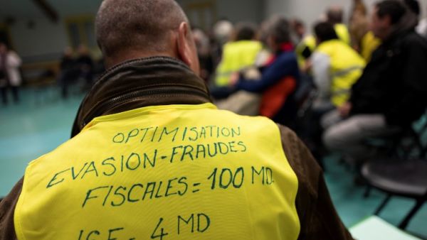 A man wearing a yellow vest with a slogan reading in French "Optimisation, tax avoidance = 100 billions, ISF = 4 billions) attends a meeting called by local members of the "yellow vest" (Gilets Jaunes) movement. (AFP)