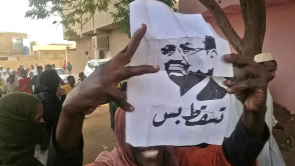 A Sudanese protester carries a portrait of President Omar al-Bashir with Arabic writing that reads "down and that is all" during an anti-government demonstration east of the capital Khartoum on February 8, 2019. (AFP)